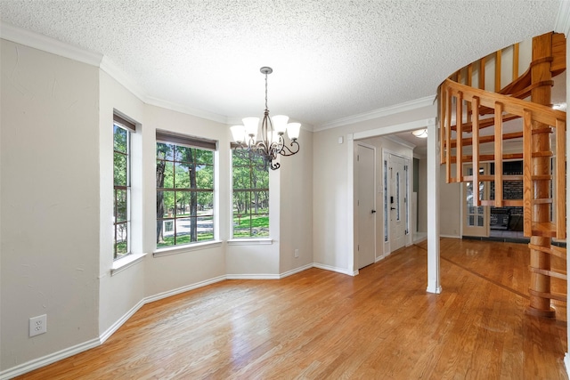 unfurnished dining area with a chandelier, light wood finished floors, a textured ceiling, baseboards, and ornamental molding