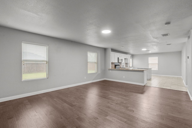 2720 Ocaso Dr, Little Elm, TX 75068 - unfurnished living room with plenty of natural light, light wood-style floors, baseboards, a textured ceiling, and recessed lighting