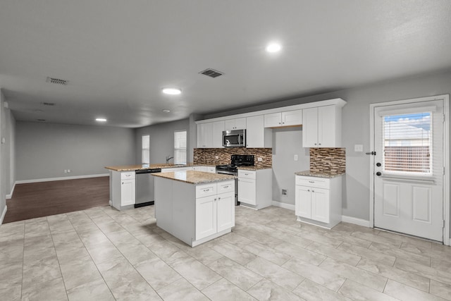 2720 Ocaso Dr, Little Elm, TX 75068 - kitchen featuring appliances with stainless steel finishes, healthy amount of natural light, decorative backsplash, a peninsula, and recessed lighting