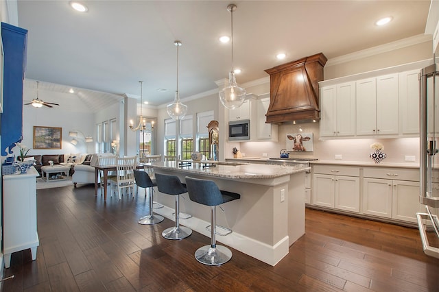 2700 Tremont Blvd, Mckinney, TX 75071 - kitchen with built in microwave, custom exhaust hood, open floor plan, white cabinetry, and crown molding