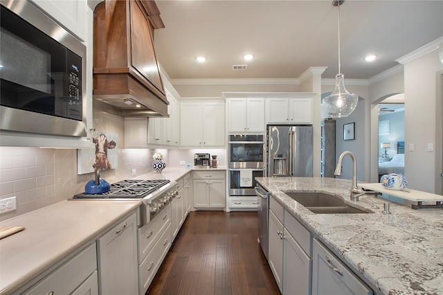 2700 Tremont Blvd, Mckinney, TX 75071 - kitchen featuring stainless steel appliances, a sink, custom range hood, arched walkways, and ornamental molding