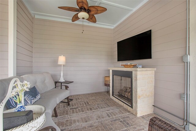 2700 Tremont Blvd, Mckinney, TX 75071 - living area with wood walls, brick patterned flooring, a ceiling fan, and a stone fireplace