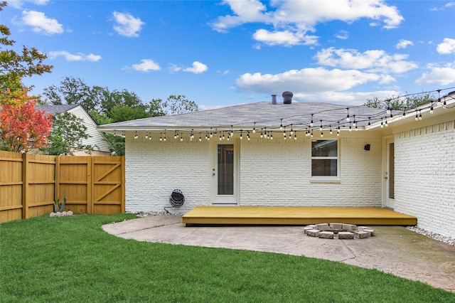 rear view of house featuring a deck, brick siding, an outdoor fire pit, roof with shingles, and a patio