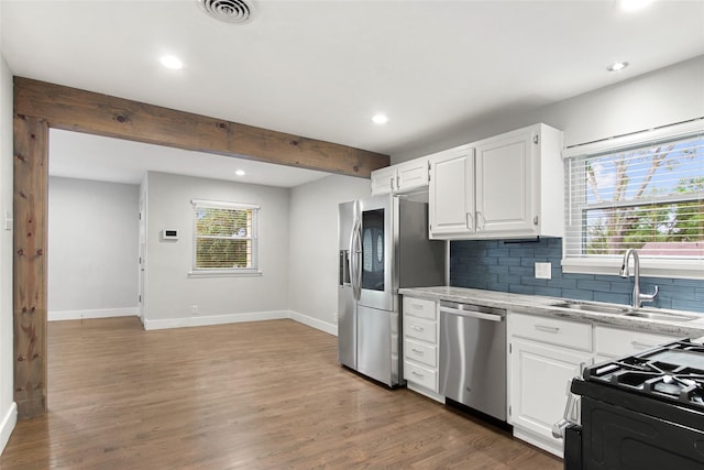 kitchen with appliances with stainless steel finishes, a sink, baseboards, recessed lighting, and tasteful backsplash