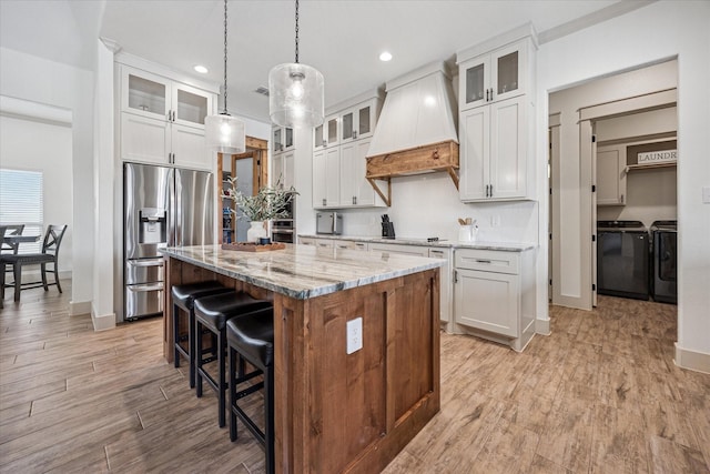 2028 Carrie Ct, Weatherford, TX 76088 - kitchen with stainless steel appliances, separate washer and dryer, premium range hood, a kitchen island, and a kitchen bar