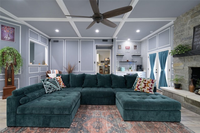 living room featuring a decorative wall, coffered ceiling, a fireplace, ceiling fan, and recessed lighting
