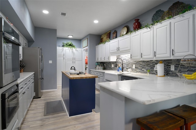kitchen featuring wooden counters, appliances with stainless steel finishes, decorative backsplash, a sink, and recessed lighting