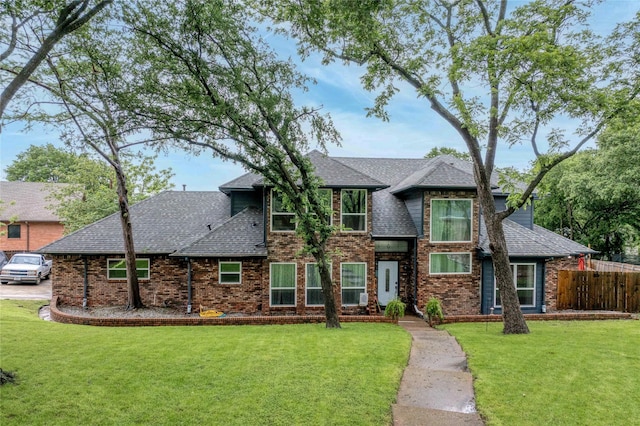 view of front facade featuring roof with shingles and brick siding