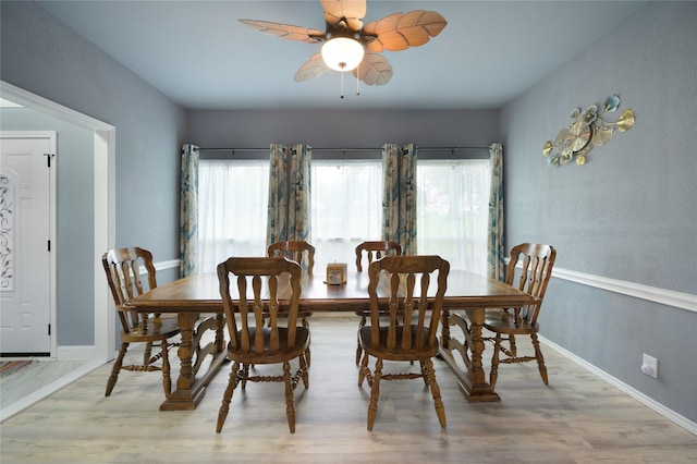 dining space featuring wood finished floors, a ceiling fan, and baseboards