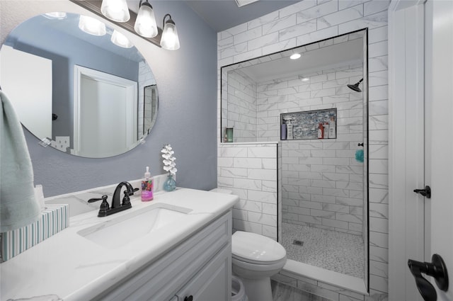 bathroom featuring tiled shower, toilet, marble look tiles, and vanity