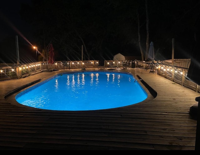 pool at twilight featuring a deck