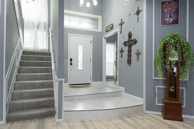 foyer entrance with stairs, wood finished floors, and baseboards