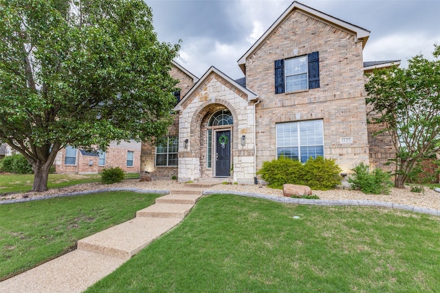 traditional-style house with a front lawn, stone siding, and brick siding