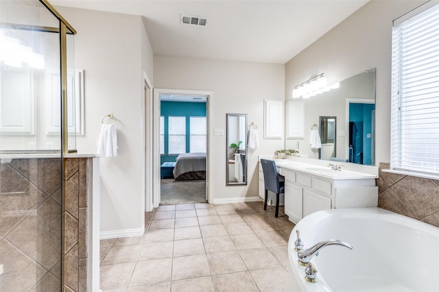 ensuite bathroom with healthy amount of natural light, vanity, a bath, and tile patterned floors