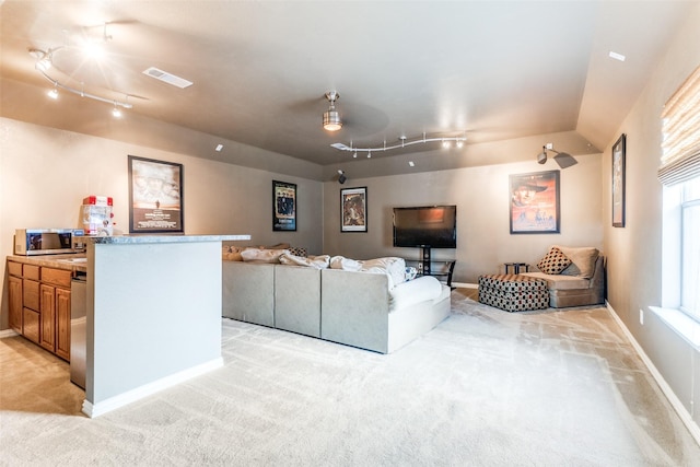 living area with light carpet, track lighting, and baseboards
