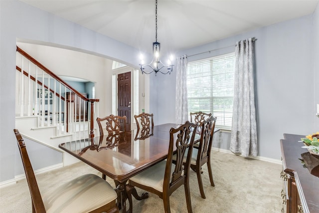 dining area with light carpet, a chandelier, arched walkways, baseboards, and stairs