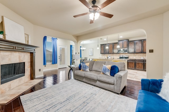 2015 Diamondback, Forney, TX 75126 - living room with arched walkways, ceiling fan, a tile fireplace, light wood-style floors, and baseboards