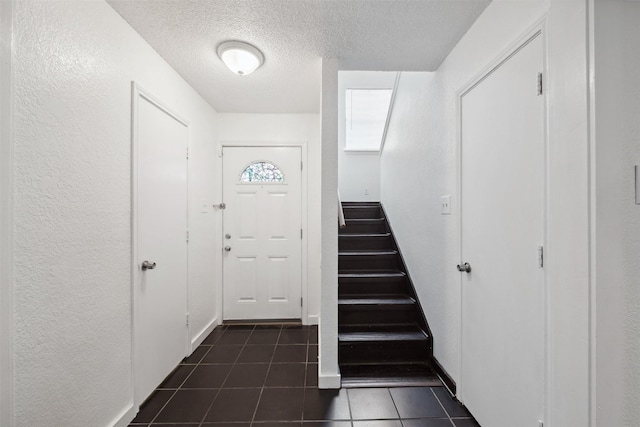 2634 Pinta Cir, Grand Prairie, TX 75052 - entrance foyer featuring dark tile patterned flooring, a textured ceiling, stairway, and a textured wall