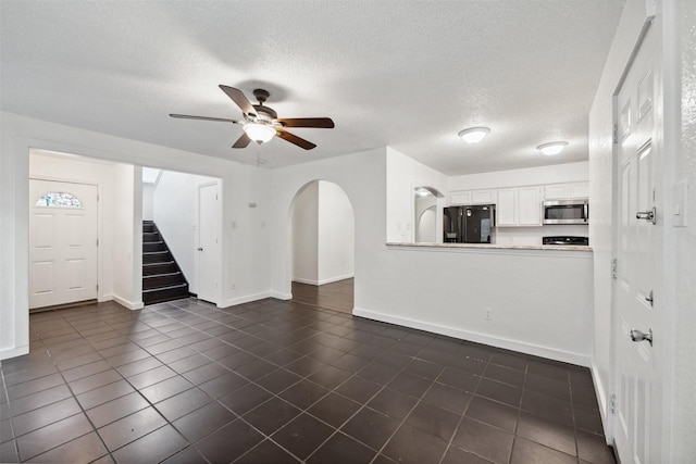 2634 Pinta Cir, Grand Prairie, TX 75052 - unfurnished living room with dark tile patterned flooring, a ceiling fan, stairway, baseboards, and a textured ceiling