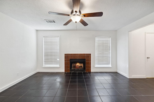 2634 Pinta Cir, Grand Prairie, TX 75052 - unfurnished living room featuring dark tile patterned flooring, a textured ceiling, ceiling fan, a tiled fireplace, and baseboards