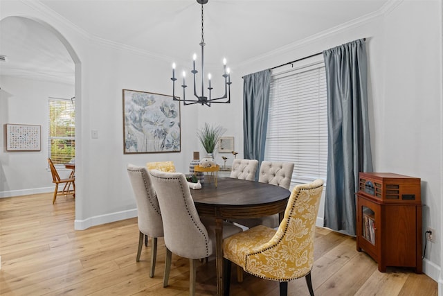 dining space with arched walkways, a chandelier, light wood-style floors, baseboards, and crown molding