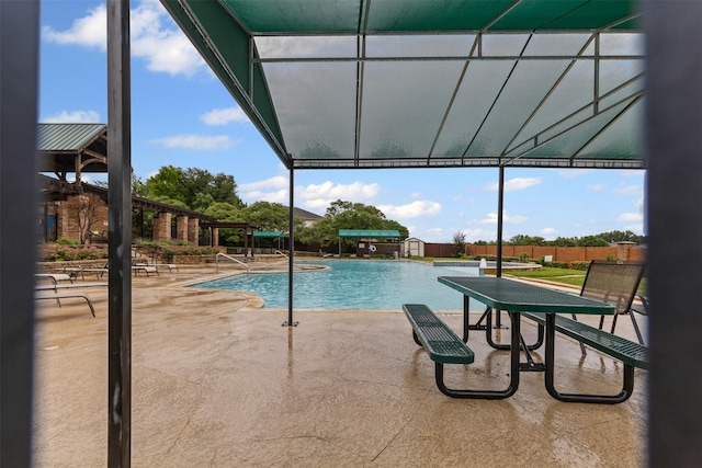 community pool with a patio area and fence