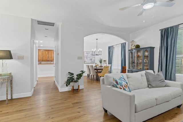 living room featuring arched walkways, a chandelier, light wood-style flooring, ceiling fan, and crown molding