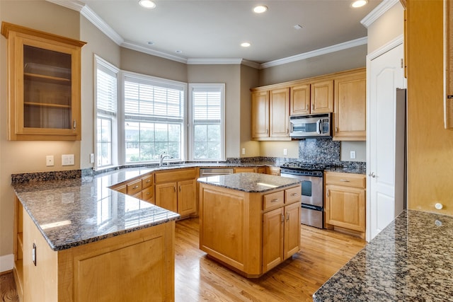 2813 Welborn St, Dallas, TX 75219 - kitchen with appliances with stainless steel finishes, light wood finished floors, dark stone counters, a peninsula, and recessed lighting