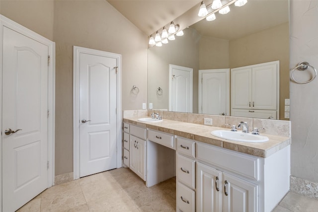 2813 Welborn St, Dallas, TX 75219 - bathroom with vaulted ceiling, double vanity, and tile patterned floors