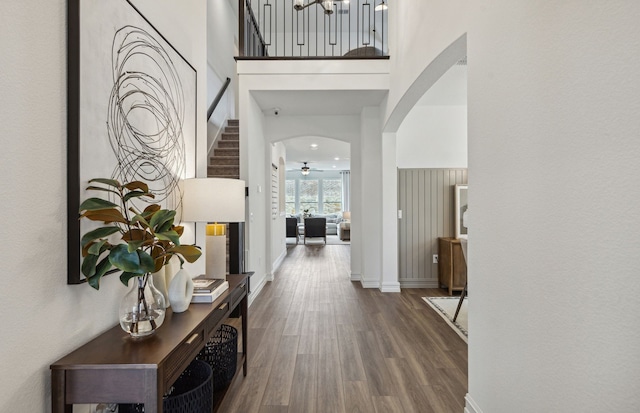 entrance foyer with wood finished floors, a high ceiling, a ceiling fan, baseboards, and arched walkways