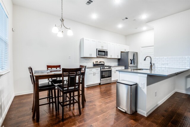 4354 Hebron St, Irving, TX 75061 - kitchen with appliances with stainless steel finishes, a sink, backsplash, a peninsula, and dark wood-style flooring