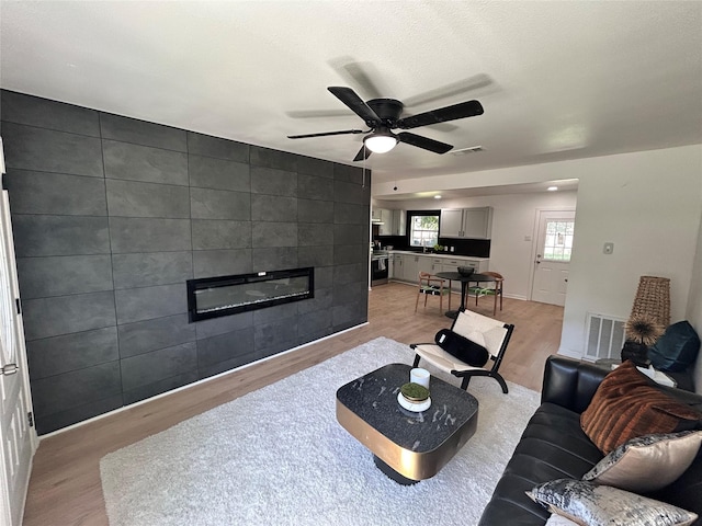 1034 Shawnee Trce, Grand Prairie, TX 75051 - living area with light wood-style flooring, a fireplace, and a ceiling fan
