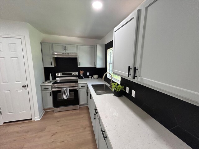1034 Shawnee Trce, Grand Prairie, TX 75051 - kitchen featuring stainless steel electric range oven, light wood-style floors, under cabinet range hood, and light countertops
