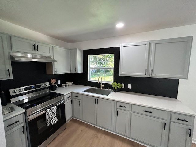 1034 Shawnee Trce, Grand Prairie, TX 75051 - kitchen featuring stainless steel electric range, under cabinet range hood, light wood-style flooring, decorative backsplash, and light countertops