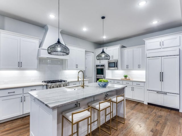 kitchen with a sink, white cabinets, appliances with stainless steel finishes, decorative backsplash, and an island with sink