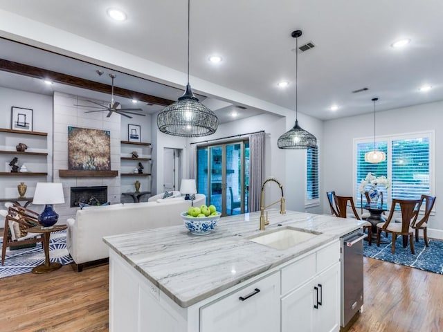 kitchen featuring a sink, light wood finished floors, white cabinets, light stone countertops, and recessed lighting