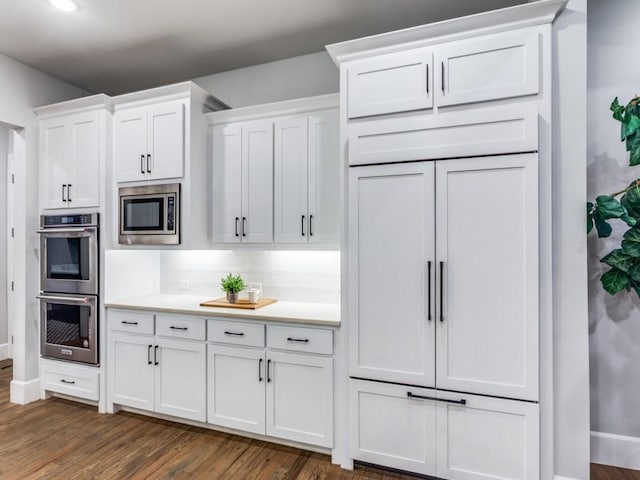 kitchen with stainless steel appliances, white cabinets, dark wood-type flooring, and light countertops