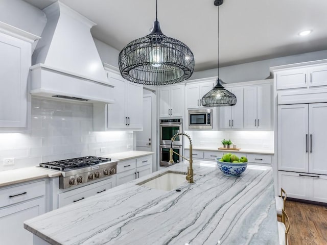 kitchen with custom exhaust hood, stainless steel appliances, a sink, white cabinets, and recessed lighting