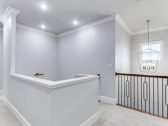 hall featuring crown molding, a chandelier, baseboards, an upstairs landing, and carpet