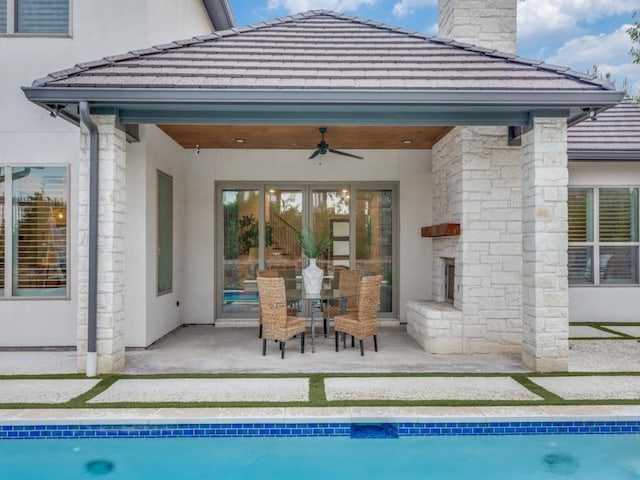 rear view of house with stucco siding, ceiling fan, a patio, an outdoor pool, and a chimney