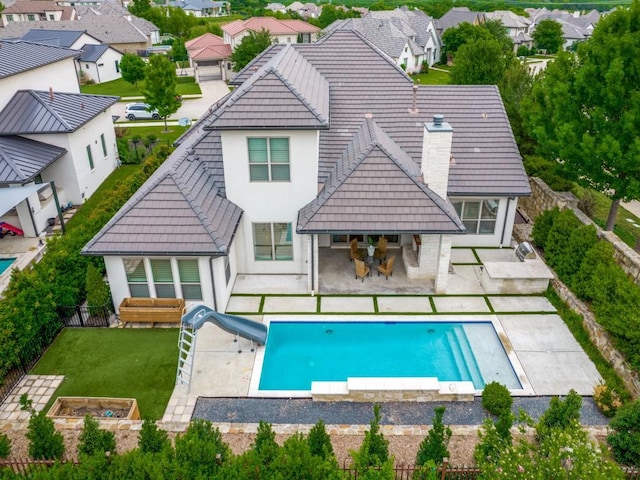 back of property featuring stucco siding, a tiled roof, a chimney, and a patio area