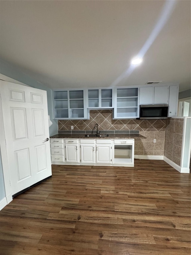 kitchen with open shelves, stainless steel microwave, a sink, dark wood-style floors, and decorative backsplash