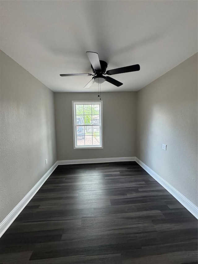 unfurnished room featuring a ceiling fan, baseboards, dark wood finished floors, and a textured wall