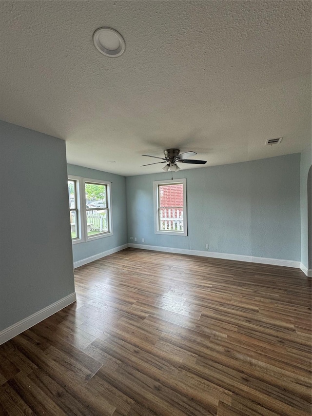 spare room featuring ceiling fan, a textured ceiling, dark wood-type flooring, and baseboards
