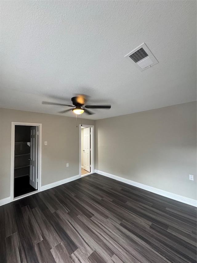 spare room with dark wood-type flooring, baseboards, a ceiling fan, and a textured ceiling