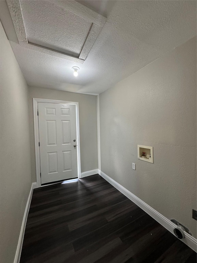 clothes washing area with dark wood-type flooring, hookup for a washing machine, baseboards, a textured ceiling, and attic access