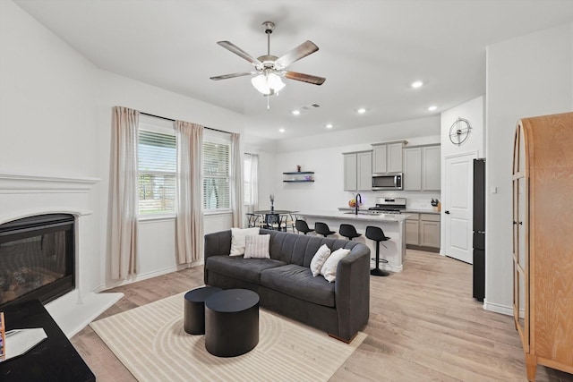 3409 Brady Starr Dr, Aubrey, TX 76227 - living area with ceiling fan, light wood finished floors, recessed lighting, baseboards, and a glass covered fireplace