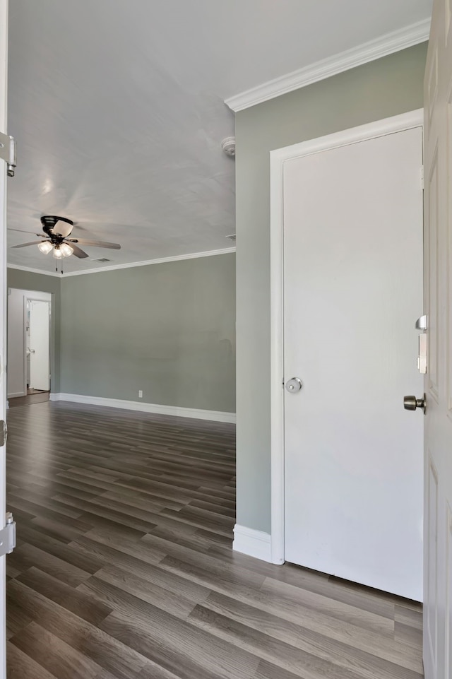 empty room with ornamental molding, ceiling fan, dark wood finished floors, and baseboards