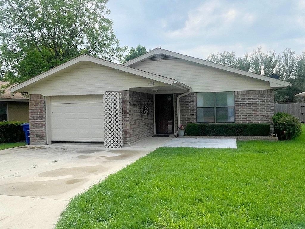 ranch-style house featuring brick siding, a garage, a front lawn, and driveway