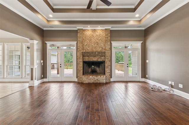 22924 County Road 223, Arp, TX 75750 - unfurnished living room featuring a ceiling fan, dark wood-type flooring, a brick fireplace, a tray ceiling, and ornamental molding
